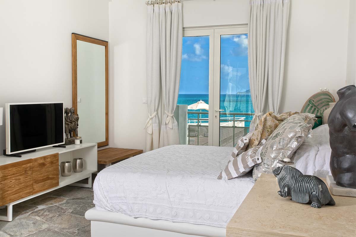 Upper-level bedroom with king-size bed, private terrace, and ocean views at Villa L'Oasis, Terres Basses, St. Martin