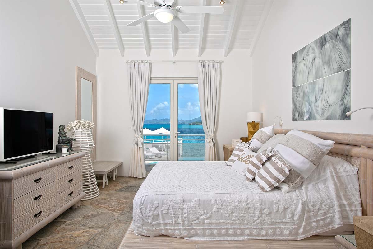 Main floor bedroom with king-size bed, ocean-view terrace, and en-suite bathroom at Villa L'Oasis, Terres Basses, St. Martin.