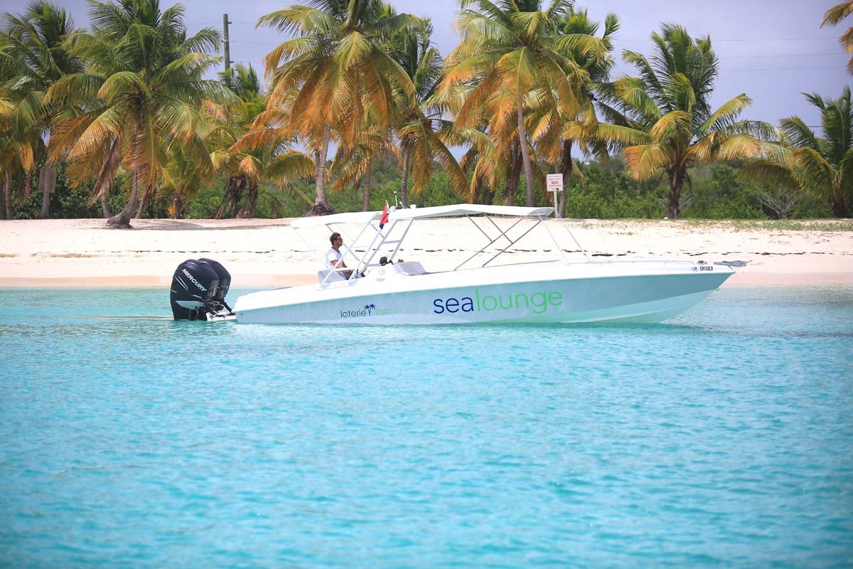 Tropical shore scene with a small white boat anchored near beach, likely SXM waters