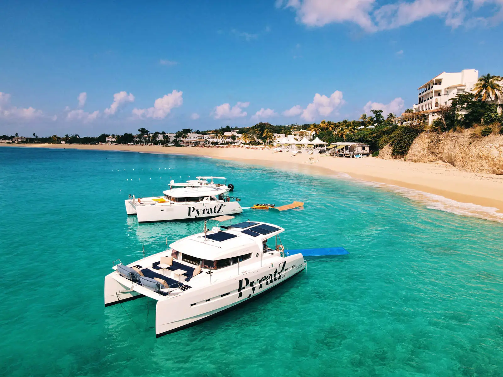Lagoon 450S power catamaran 'Galaxy' anchored in turquoise waters off St. Maarten, showcasing paddle boards, a kayak, and a floating mat.