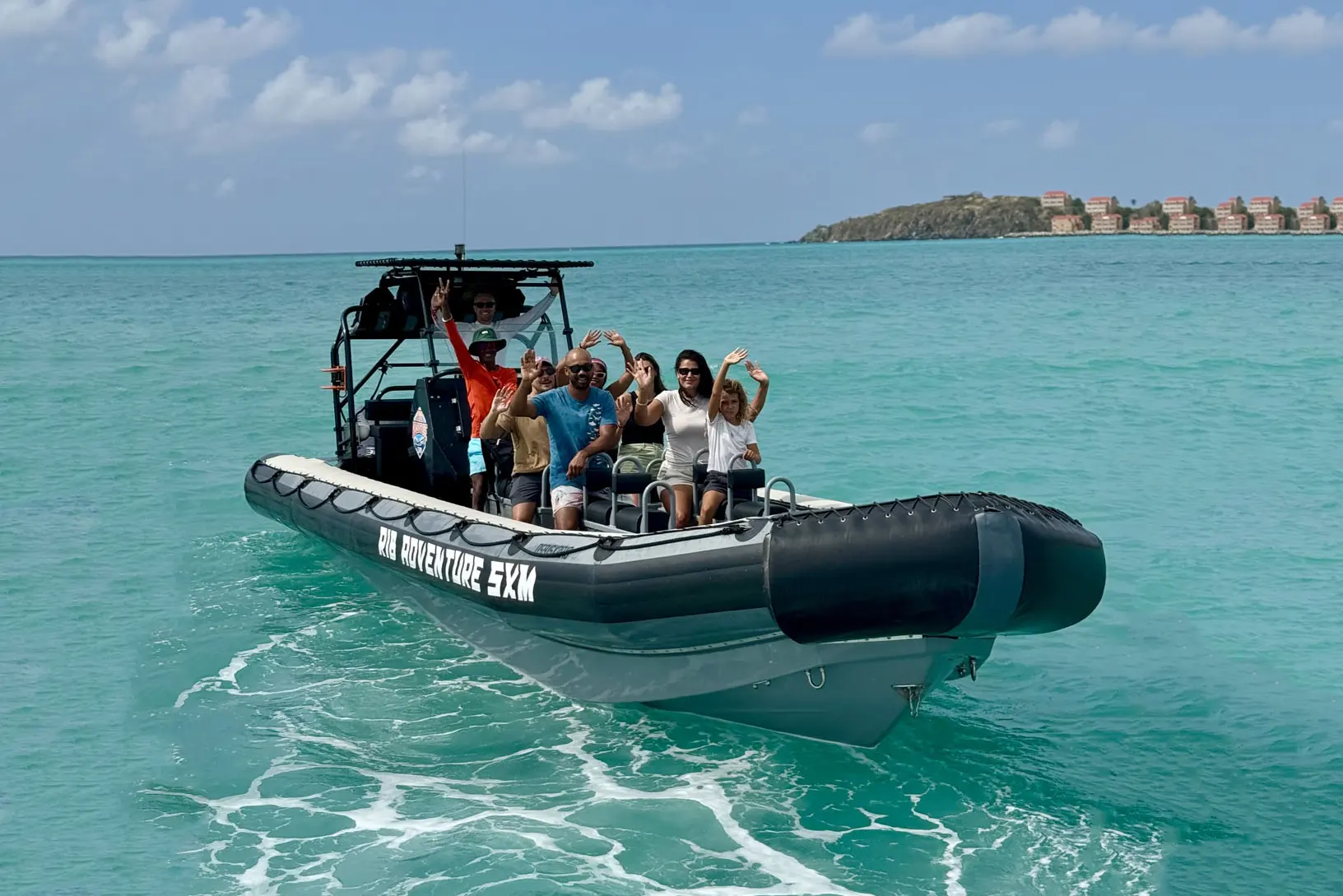 Front-facing RIB speedboat cutting through turquoise St. Maarten waters, foamy white wake.